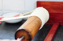 Wrapping the flat dough strip around the spit — image 1